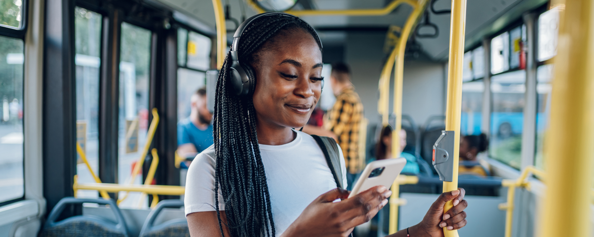 Ein Mädchen im teenage Alter steht im Bus und hört fröhlich Musik über Kopfhörer