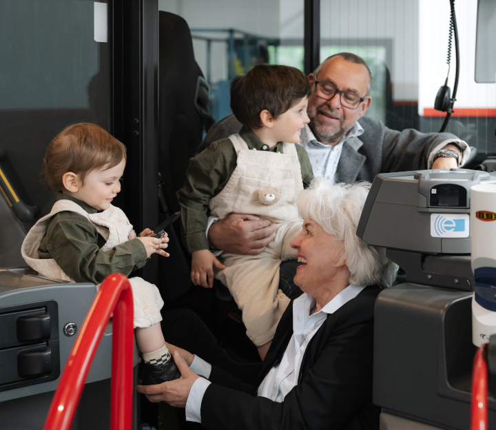 Familienmensch Willi und Katrin sitzen mit ihren Enklkindern lachend im Bus