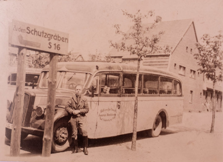 1943 Ein Mann in Uniform lehnt sich an einem altentümlichen Bus an